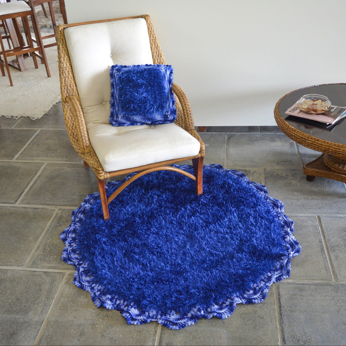 Circulo Natural Luxury Decor - Fluffy Effect Yarn, 180 m / 280 g - Blue shaggy rug on a stone floor with a chair and table in the background.