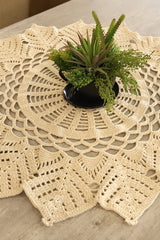 Circulo Barroco Natural Brilho  - Natural Cotton Yarn Gold/Silver, 657m / 433m, 400g - A round cream-colored crocheted doily with an intricate lace pattern, styled on a light wood tabletop with a small potted succulent plant in the center.