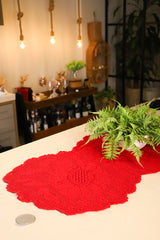 Circulo ANNE - 100% mercerized Cotton Yarn, 500m / 147g - Red crocheted table runner on a white surface with a blurred background of bottles and decor.