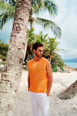Circulo Jeans – 100% Brazilian Cotton Denim Effect Yarn (132m/100g) - A man wearing a bright orange knit sleeveless top and white pants stands on a sandy beach next to a palm tree, with ocean and more palm trees in the background.